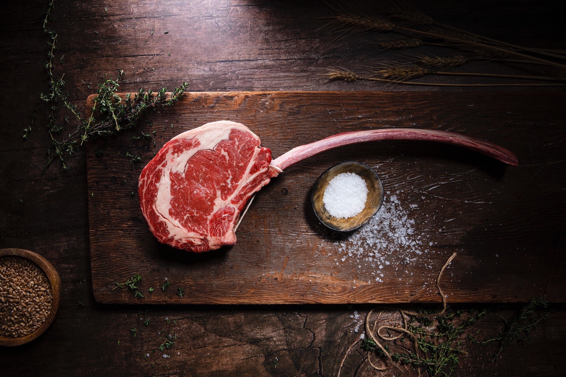 Tomahawk Steak auf Holzplatte mit Salz und Gewürzen